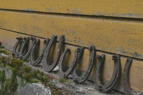 Background surface of very old and rusty horseshoes placed near the wall Stock Photos