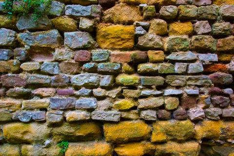 Background texture and pattern of a weathered rough stone wall with rough hew Stock Photos