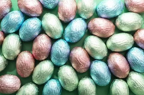 Background, texture closeup small Easter chocolate eggs, sweets wrapped in Stock Photos