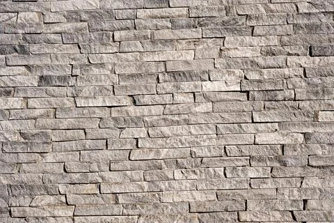 Background texture of a grey wall with long narrow bricks Stock Photos