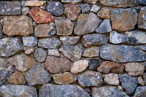 Background texture of masonry wall made of multicolored stones. Stock Photos