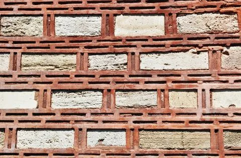Background, texture. A stone wall made of narrow red bricks. Stock Photos