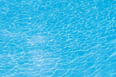 Background with the texture of the water in the pool of blue color that spark Stock Photos