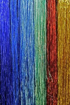 Background of thin multicolored Christmas strands, shiny decorations. Fotos de archivo
