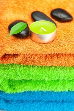 Background of the three multi-colored bath towels, black spa stones, green le Stock Photos