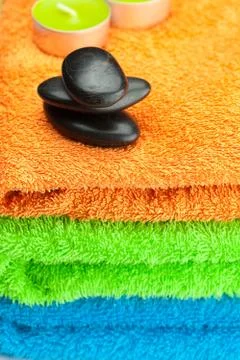 Background of the three multi-colored bath towels, black spa stones, green le Stock Photos