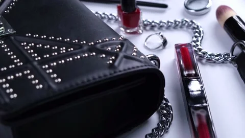 Background with trendy black handbag and decorative cosmetics, nail polish, make Stock Footage 209976076