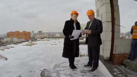 In the background, unrecognizable builder working in an orange vest and helmet. Stock-Footage 58686241