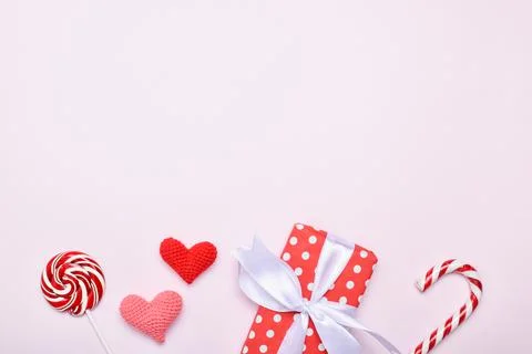 Background for Valentine's Day. Two lollipops, a gift and hearts on a pink ba Stock Photos