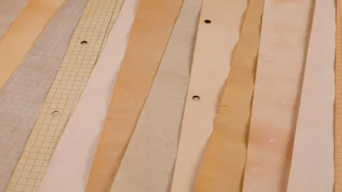 A background of various beige, cream, and light brown paper strips. 스톡 동영상 329729137