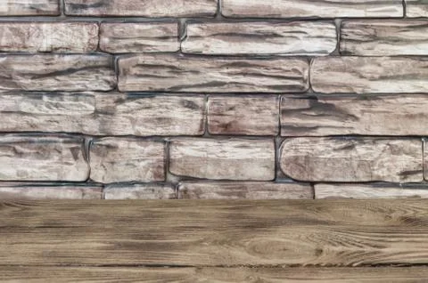 The background is a wall of large brown bricks and wooden boards. Stock Photos