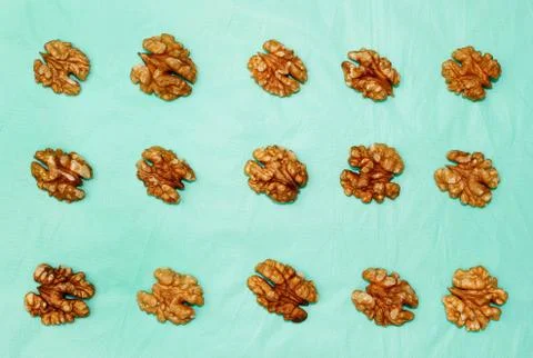 Background of walnut kernel halves pattern on turquoise background. Stock Photos