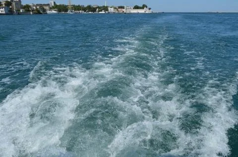 Background with wave and foam, trace on the surface of the water behind the f Stock Photos