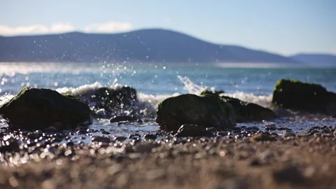 Background Waves crashing on rocks on the beach. A light tide in the lagoon on Stock Footage 250421486
