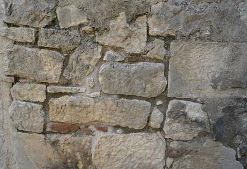 Background of weathered stone wall with ancient stonework. Stock Photos