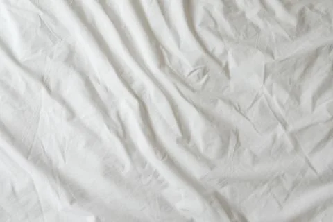 Background of white rumpled sheets. Bed linen with wrinkles in day light. Hor Stock Photos