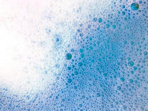 Background with white soap foam in blue bright water in bathroom Stock Photos