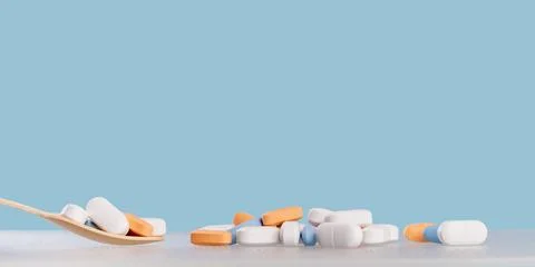 Background of white tablets or pills on blue table. Medicine and pharmacy Stock Photos