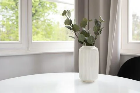 Background of white vase with artificial eucalyptus on white table and wind.. Stock Photos