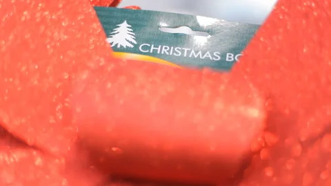 Background:Huge red sparkling bow on the background of the inscription Christmas Stock Footage 98569483