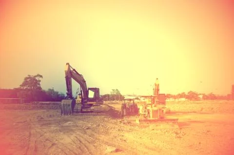 The backhoe and tractor working on the sunset time 写真素材