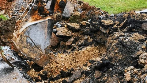 Backhoe digging leaking water pipes Stock Footage 118955577