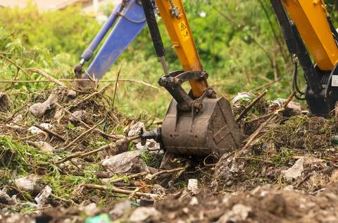 Backhoe digging soil at construction site. Bucket of backhoe digging soil. Cl 스톡 사진