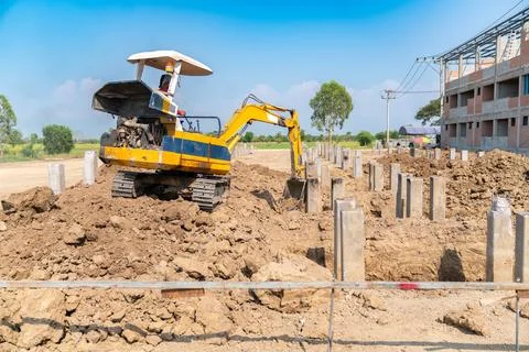 Backhoe digging soil for foundation work at a building construction project. Foto stock