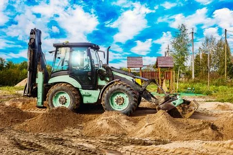 Backhoe is executing ground shaping work as part of site preparation proces.. Stock Photos