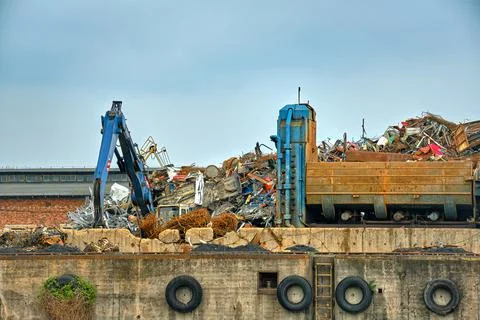 Backhoe loader and big construction debris in river port in overcast day. Stock Photos