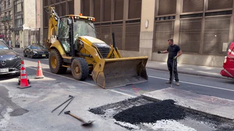 Backhoe Loader and Worker With Pry Bar Lift Steel Road Plate on Manhattan Street Stock-Footage 347894796