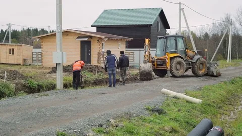 Backhoe loader digging soil. Workers are digging with shovels. Construction site Video stock 73042695