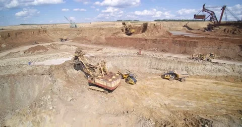 Backhoe loader puts sand into quarry dump truck aerial Stock Footage 131942778