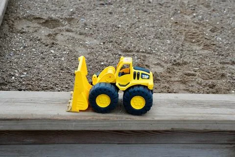 Backhoe loader in yellow removing rock, car toy for kids play around outsidein 库存照片