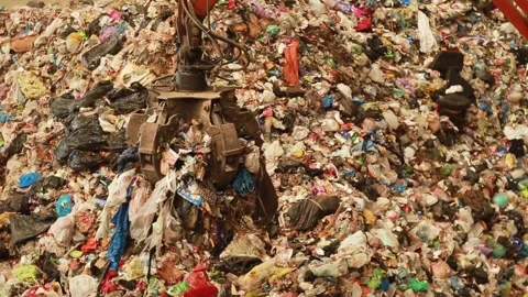 Backhoe loader's pincer grip grabs the trash and throws it into the shredder Stockbeeldmateriaal 246771177