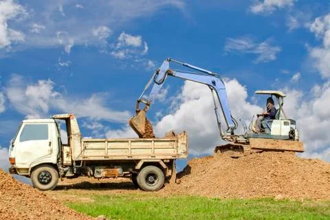 Backhoe loading a dump truck. Stock Photos