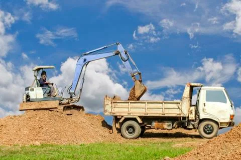 Backhoe loading a dump truck. Stock Photos