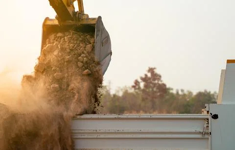 Backhoe loading soil into heavy duty dump truck at construction site. Crawl.. 库存照片