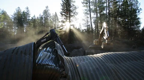Backhoe moving dirt around corrugated metal Stock Footage 51596892