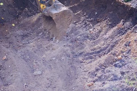 A backhoe working bucket in the ground at a construction site close-up Stock Photos