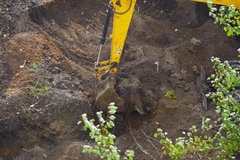 Backhoe working bucket in the ground at construction site closeup Stock Photos
