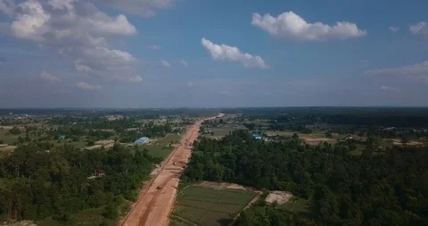 Backing up by drone above construction road between forest in fields Stock Footage 109077702