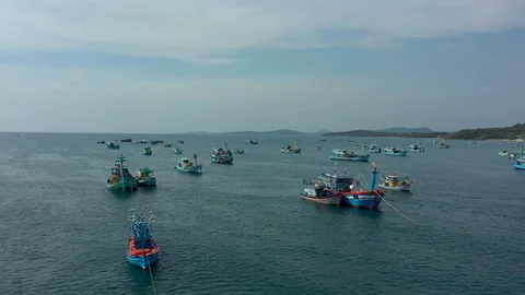 Backing up flying back panning back above lots of fishing boats floating on sea Stock Footage 124214962