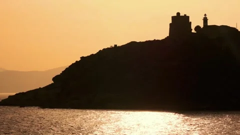 Backlight image of a lighthouse on the cliff during the golden hour Stock Footage 253489074