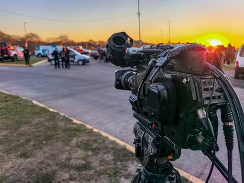 Backlight shot of television journalists broadcasting breaking news outdoors Stock Photos