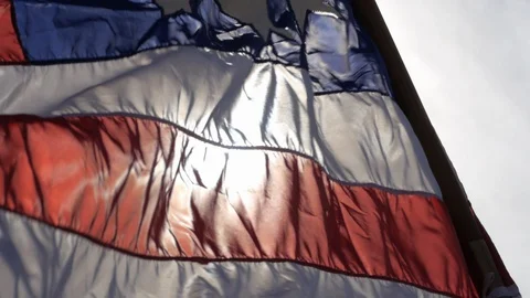Backlit 13-star American flag catches the wind with sun behind it Stock Footage 105393751