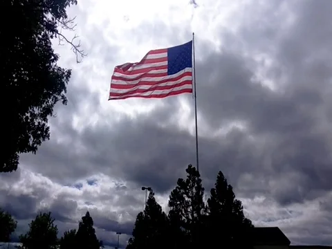 Backlit American Flag with Storm Clouds Stock Footage 81415385