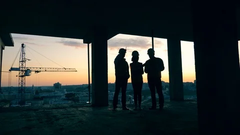 Backlit architects talking in a building under construction during sunset. Video stock 116540281