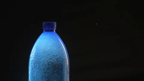 Backlit blue plastic bottle of still natural water with tiny gas bubbles. Vídeo Stock 91679395