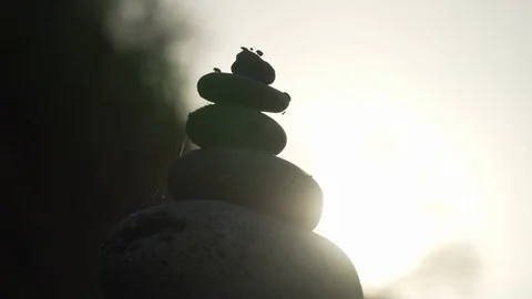 Backlit cairn at the beach with bugs sitting on top Stock Footage 128363914